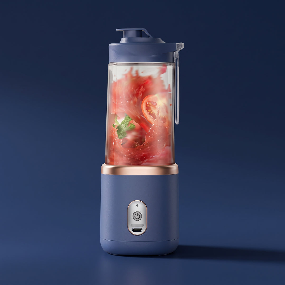 A portable electric blender with a slate blue base and lid, rose gold metallic accents, and a clear container filled with red fruit and green leafy herbs, set against a dark blue background.
